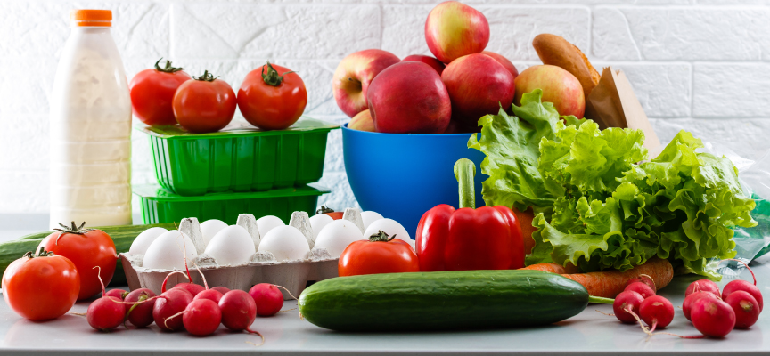 Fresh vegetables, fruits, eggs, and milk on a kitchen counter available for online grocery ordering on the Smiles Marketplace.