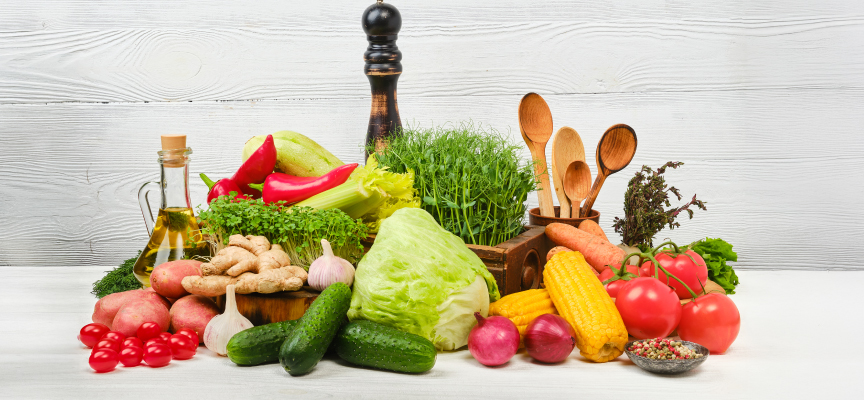 Assorted fresh vegetables, fruits, and olive oil ingredients arranged on a kitchen counter for online grocery ordering.
