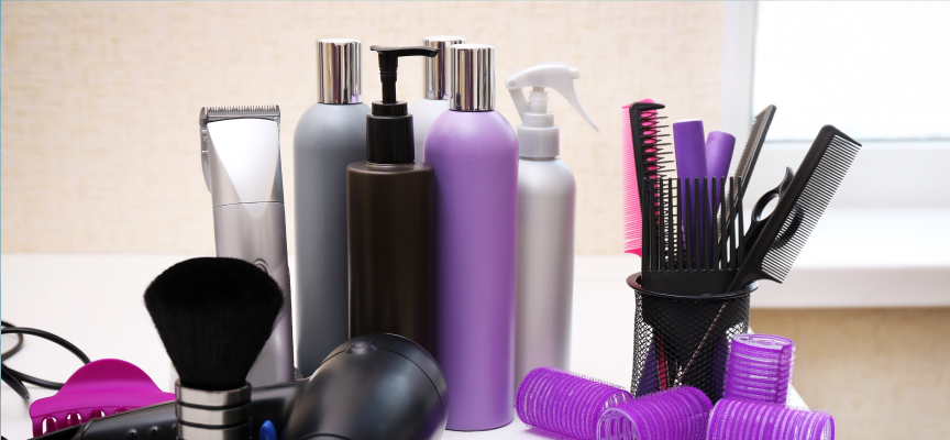 Array of professional salon equipment, hair salon sprays, makeup brushes, and purple hair rollers ready for an online home service booking checkout.