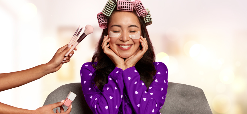  Woman with hair rollers smiling while receiving a professional at-home makeover and beauty treatment from a service champion in Dubai.