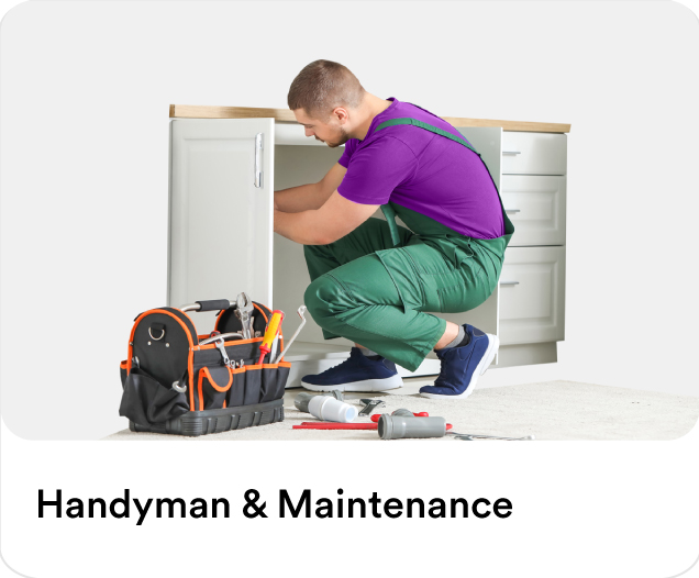 Professional repairman fixing kitchen cabinets next to an open toolkit box to illustrate handyman services and home maintenance in the UAE.