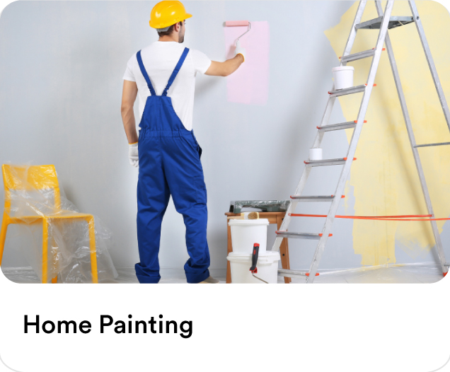 Professional painter in blue overalls and a yellow hard hat painting an interior wall pink to showcase residential home painting services.