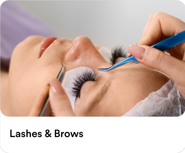 : Beauty technician applying eyelash extensions and brow mapping tweezers to a customer during an at-home lash and brow beauty treatment.